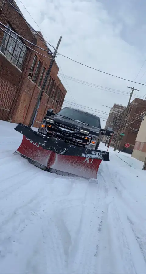 Commercial snow plow truck clearing snow between buildings by The Guy Outdoor Services