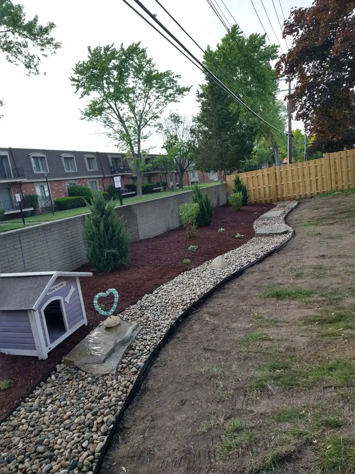 Dry creek bed with river rock and landscape plantings in Metro Detroit backyard