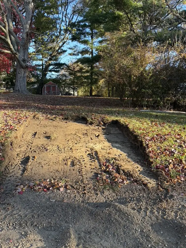 Yard regrading project redirecting water away from a home foundation