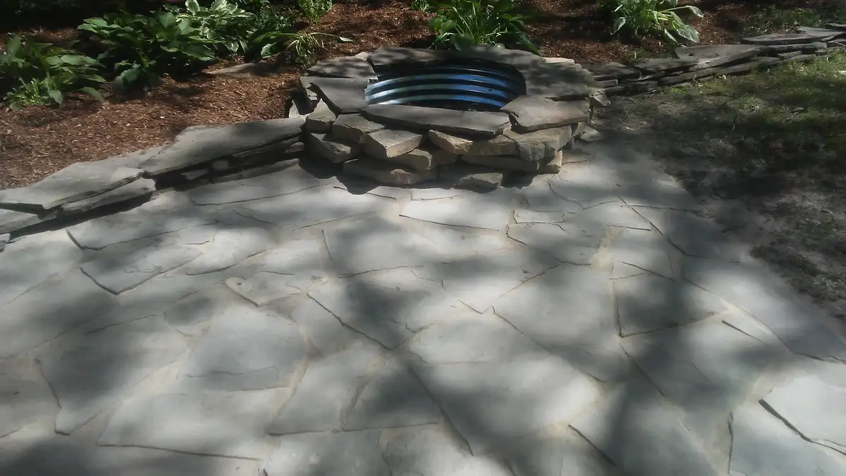 Built-in fire pit with seating area on paver patio by The Guy Outdoor Services