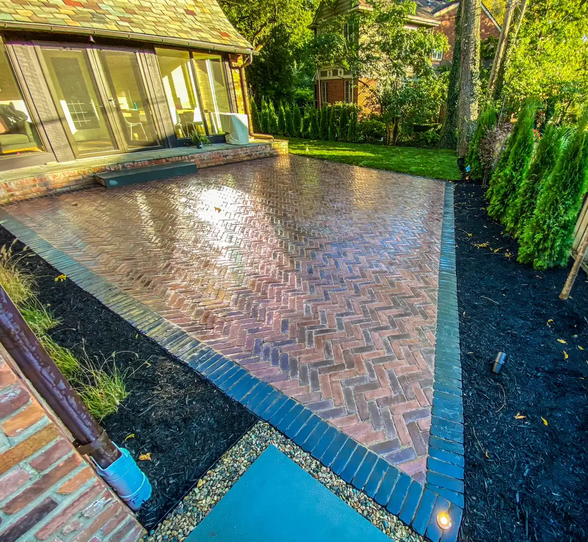 Professional landscape lighting on brick paver patio at dusk