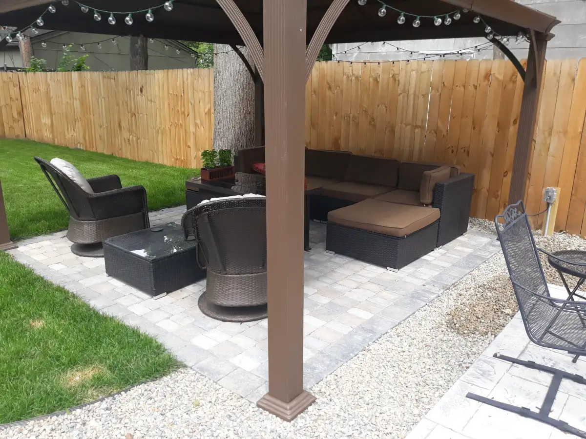 Pergola with string lights over paver patio and outdoor seating by The Guy Outdoor Services