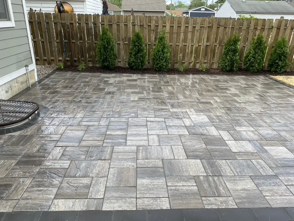 Gray natural stone paver patio with arborvitae privacy plantings
