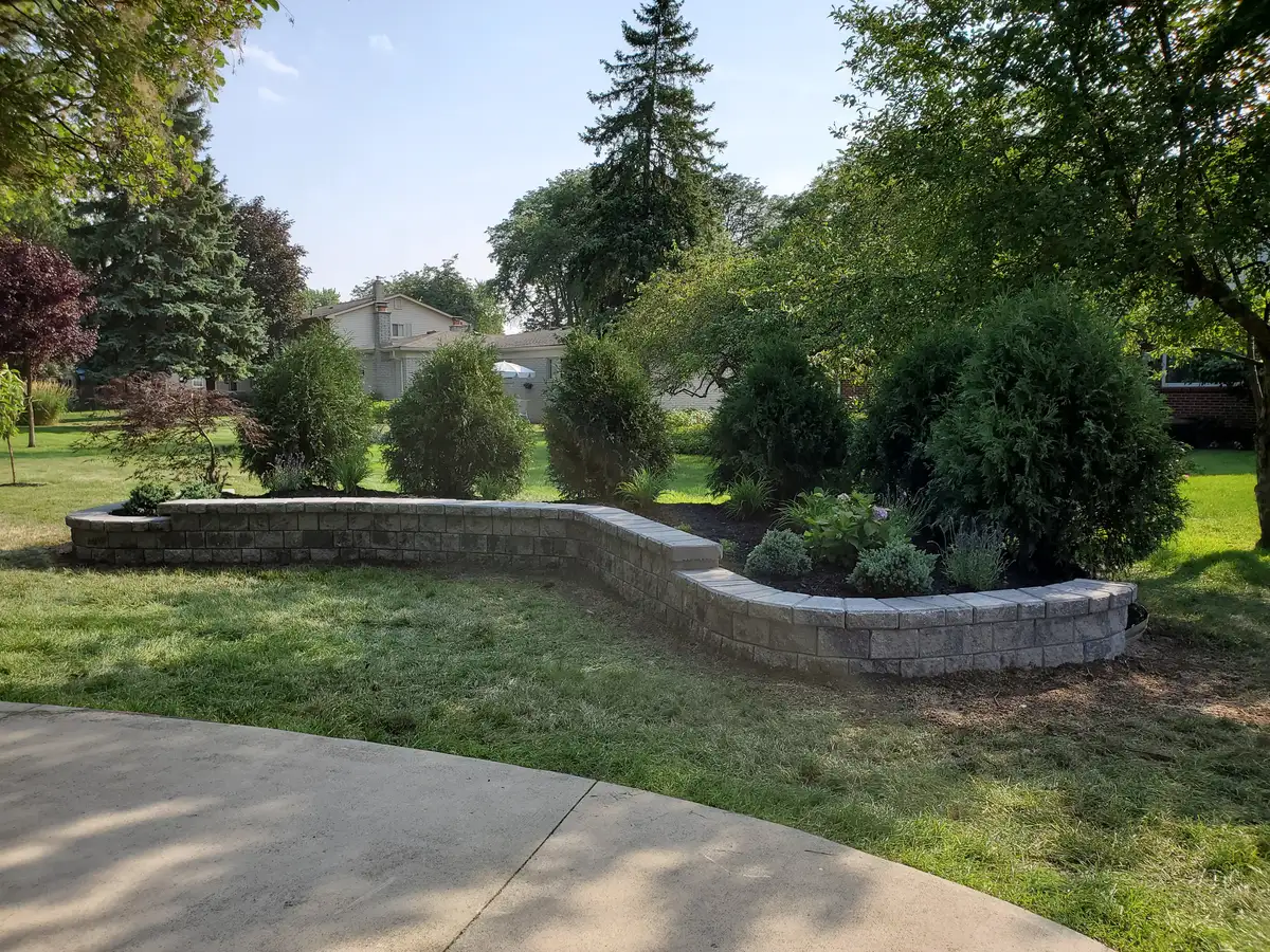 Long curved paver block retaining wall with mature trees and shrubs