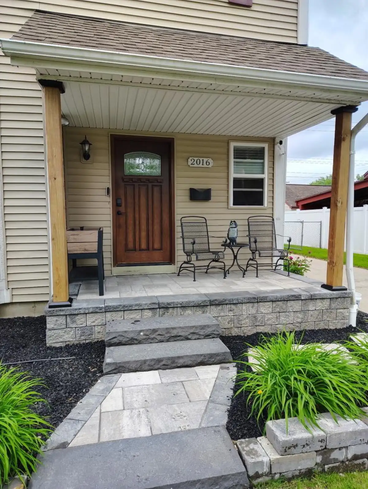 Paver walkway and stone porch steps with mulch beds and ornamental grasses by The Guy Outdoor Services