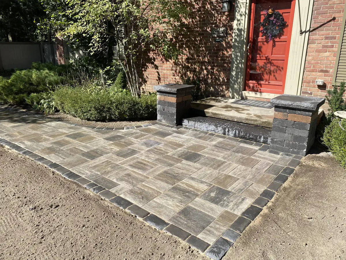 Paver entry with pillar accents and lush landscaping