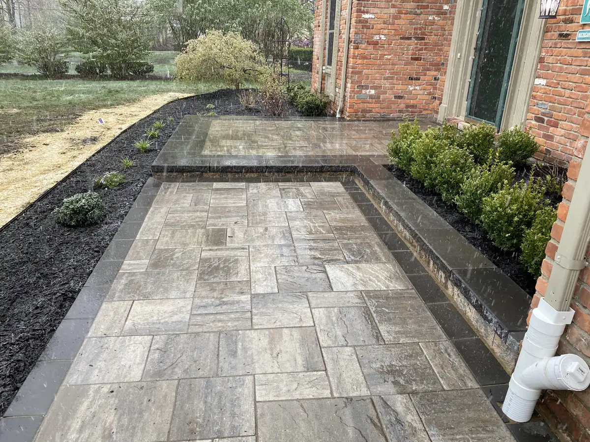 Finished brick paver patio with dark charcoal border and fresh mulch beds by The Guy Outdoor Services