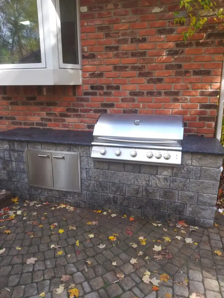Built-in stainless steel outdoor grill with stone counter and granite top by The Guy Outdoor Services