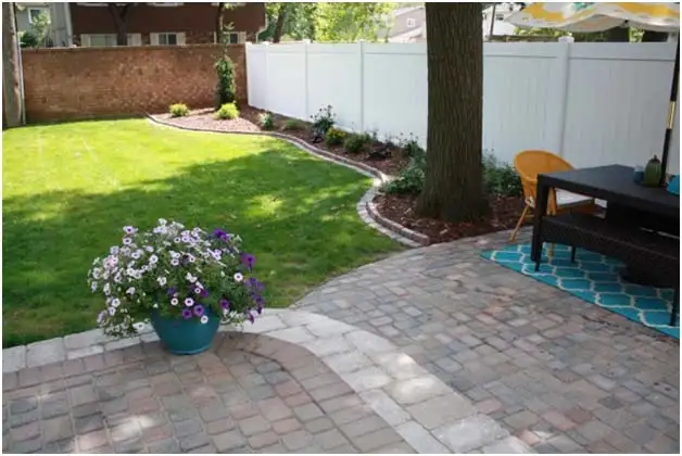 Colorful backyard patio with outdoor seating and flower planters by The Guy Outdoor Services