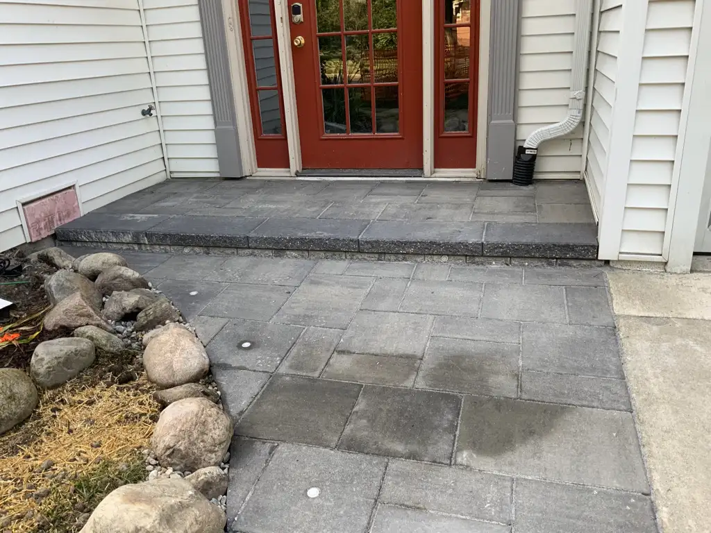 Finished paver steps and entry with red doors and boulder border
