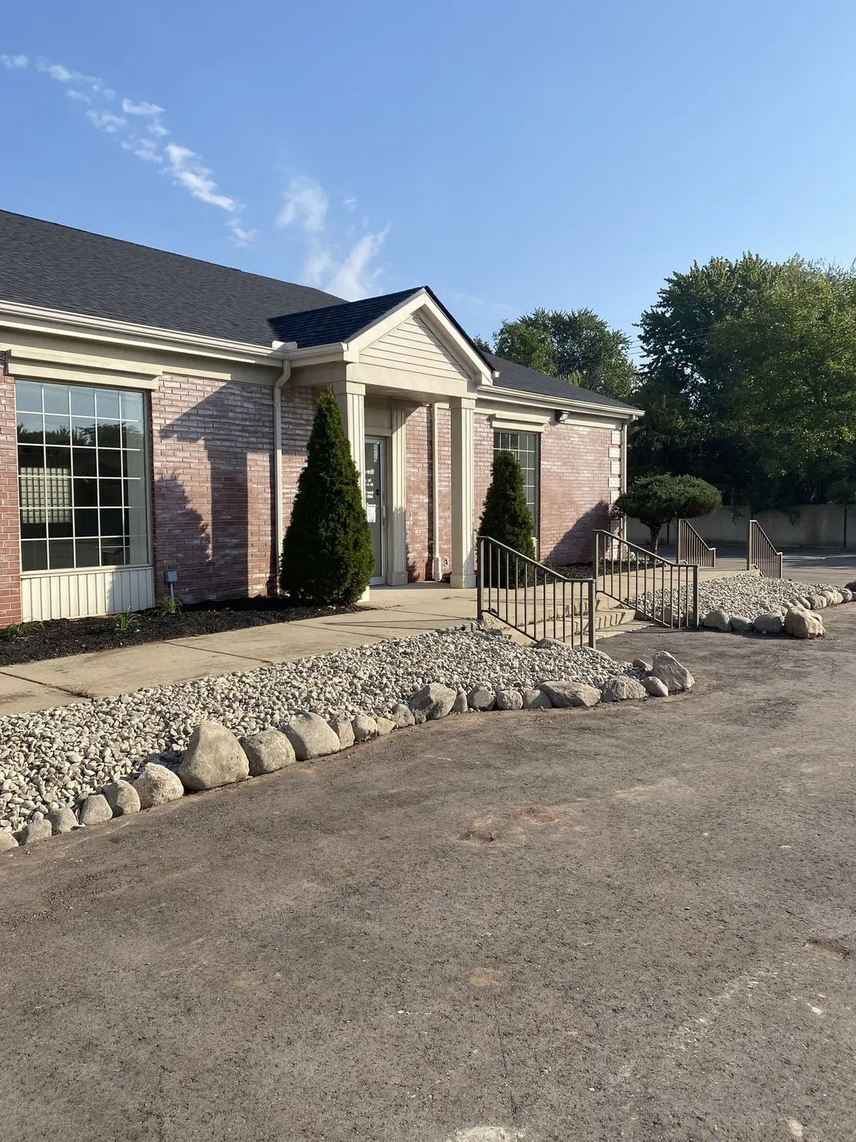 Professional drainage rock bed and boulder edging along commercial building foundation in Metro Detroit