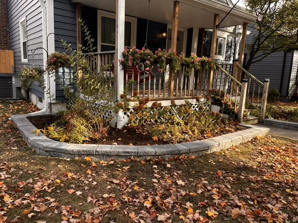 Curved block retaining wall planter with fall plantings at residential entrance