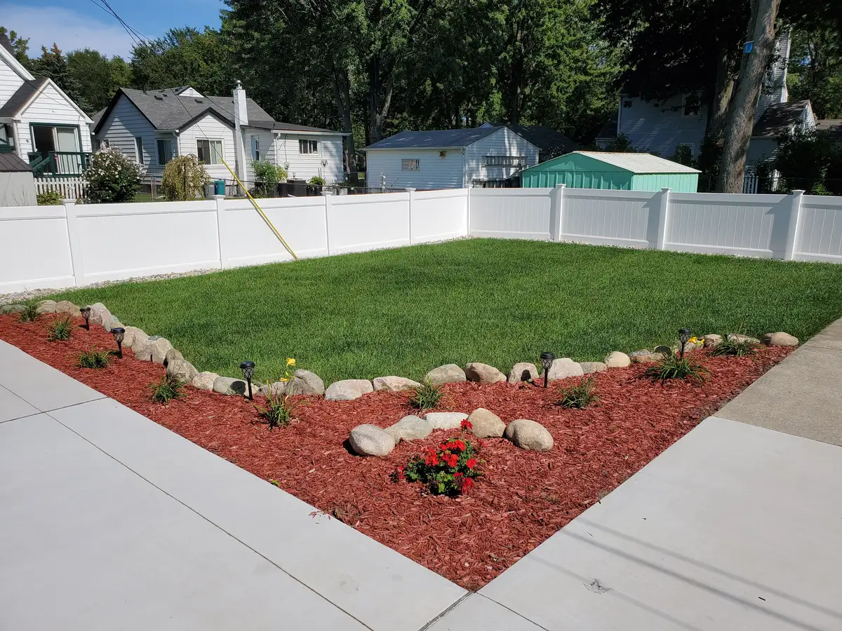 New green lawn bordered by boulders and mulched planting beds