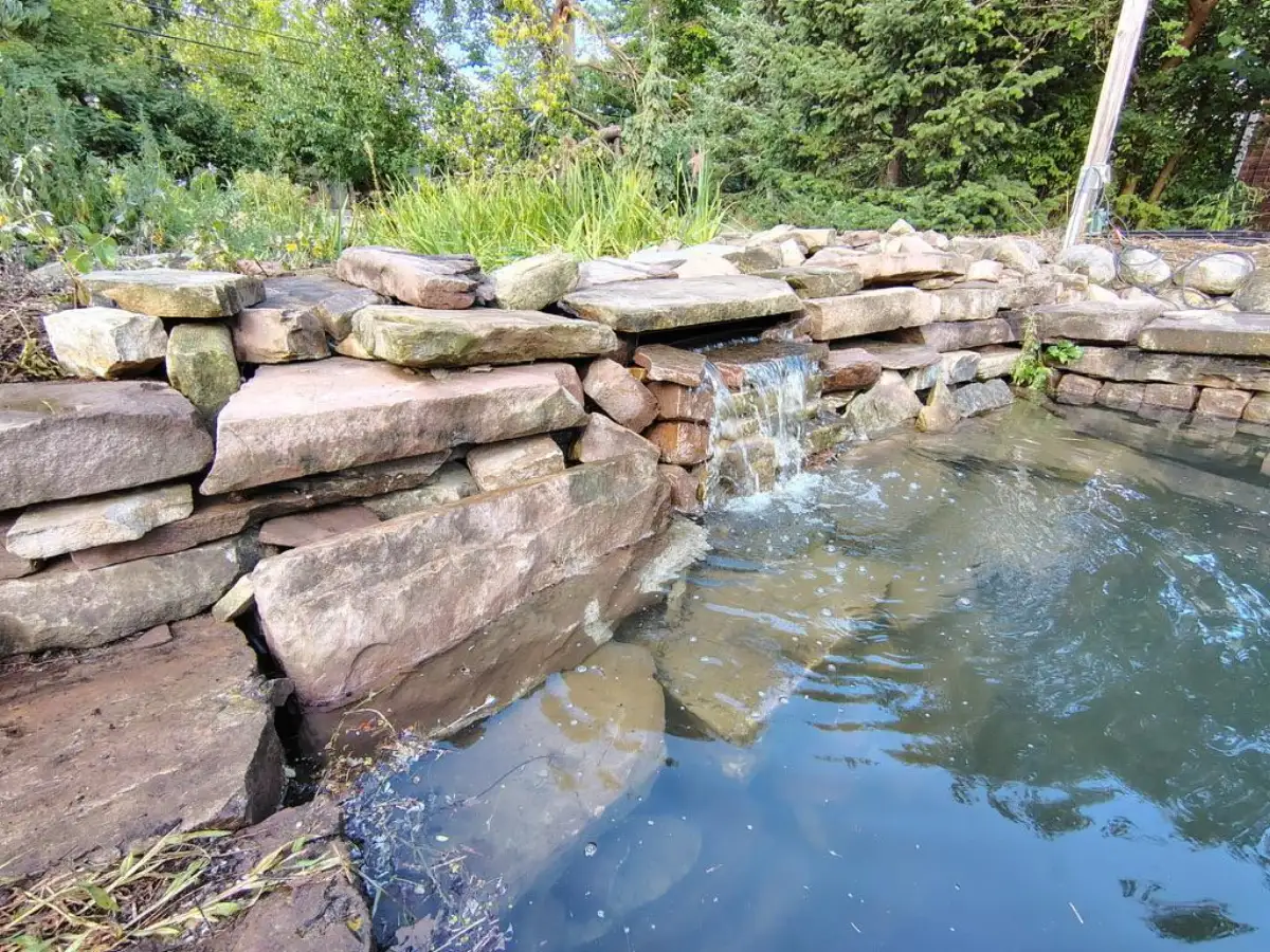 Natural stone boulder waterfall cascading into pond